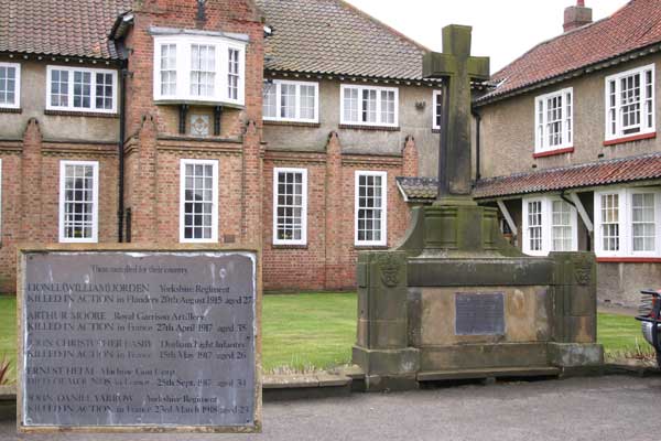 The War Memorial at East Rounton is in front of the Village Hall. The names of those who fell is on a metal plaque fitted to the front of the memorial (inset).